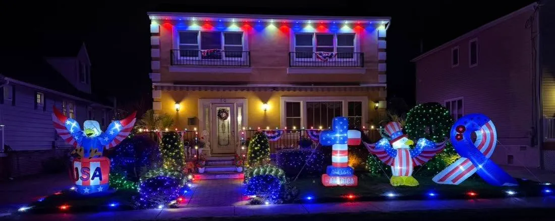 Home in red, white, and blue permanent lighting with patriotic yard decorations