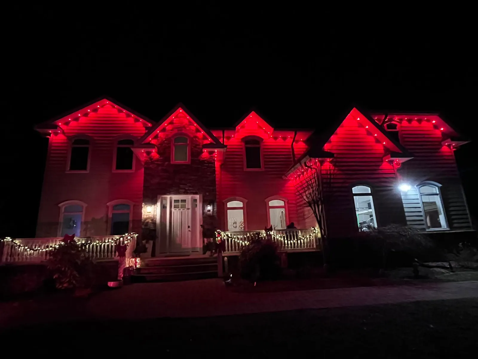 Large estate home fully outlined in red permanent lighting at night