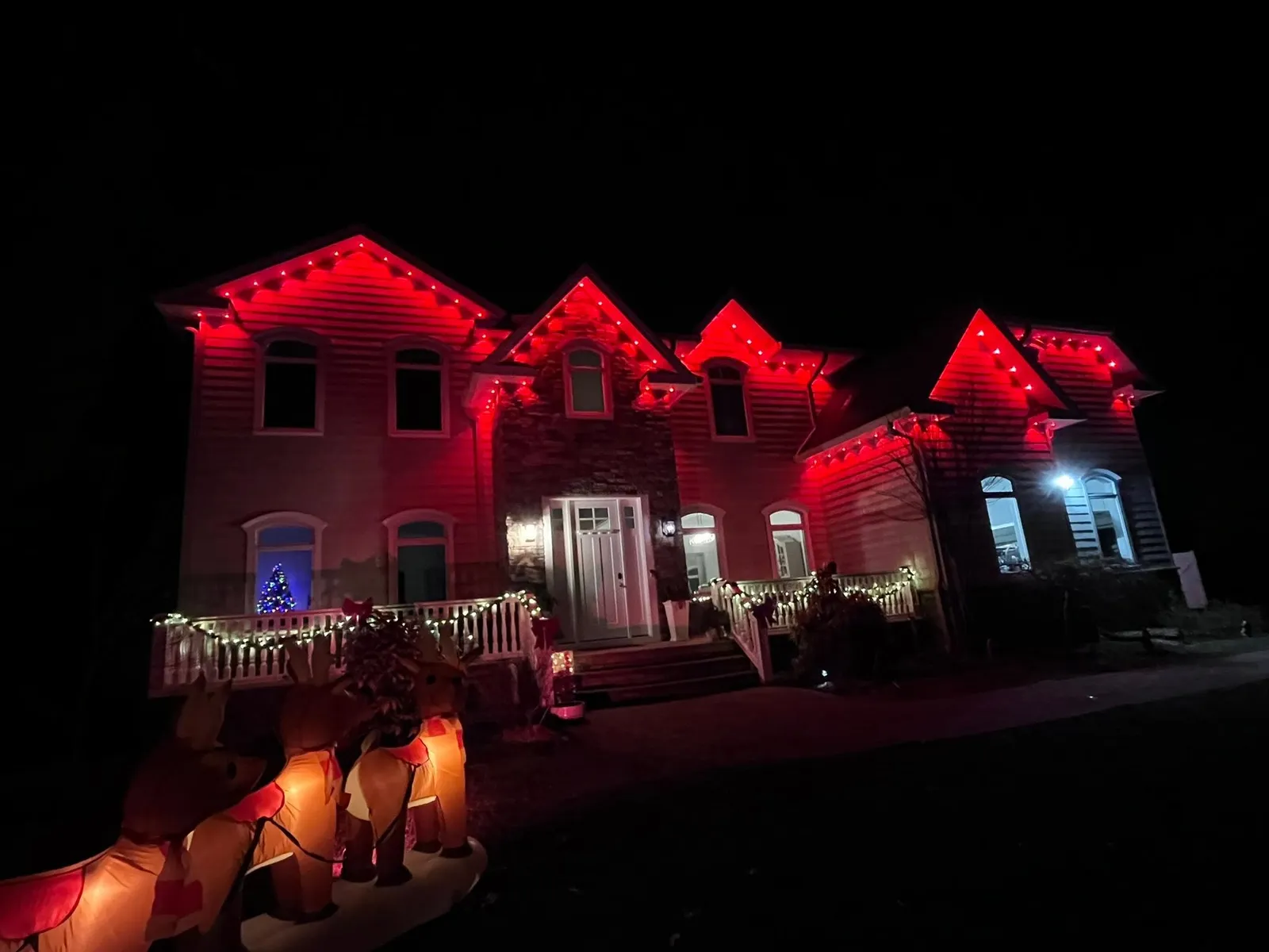 Large home glowing red from permanent eave lighting for the holidays