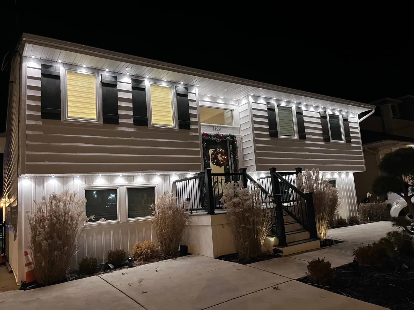 Stucco two-story with red permanent eave lighting and white accent lighting at dusk