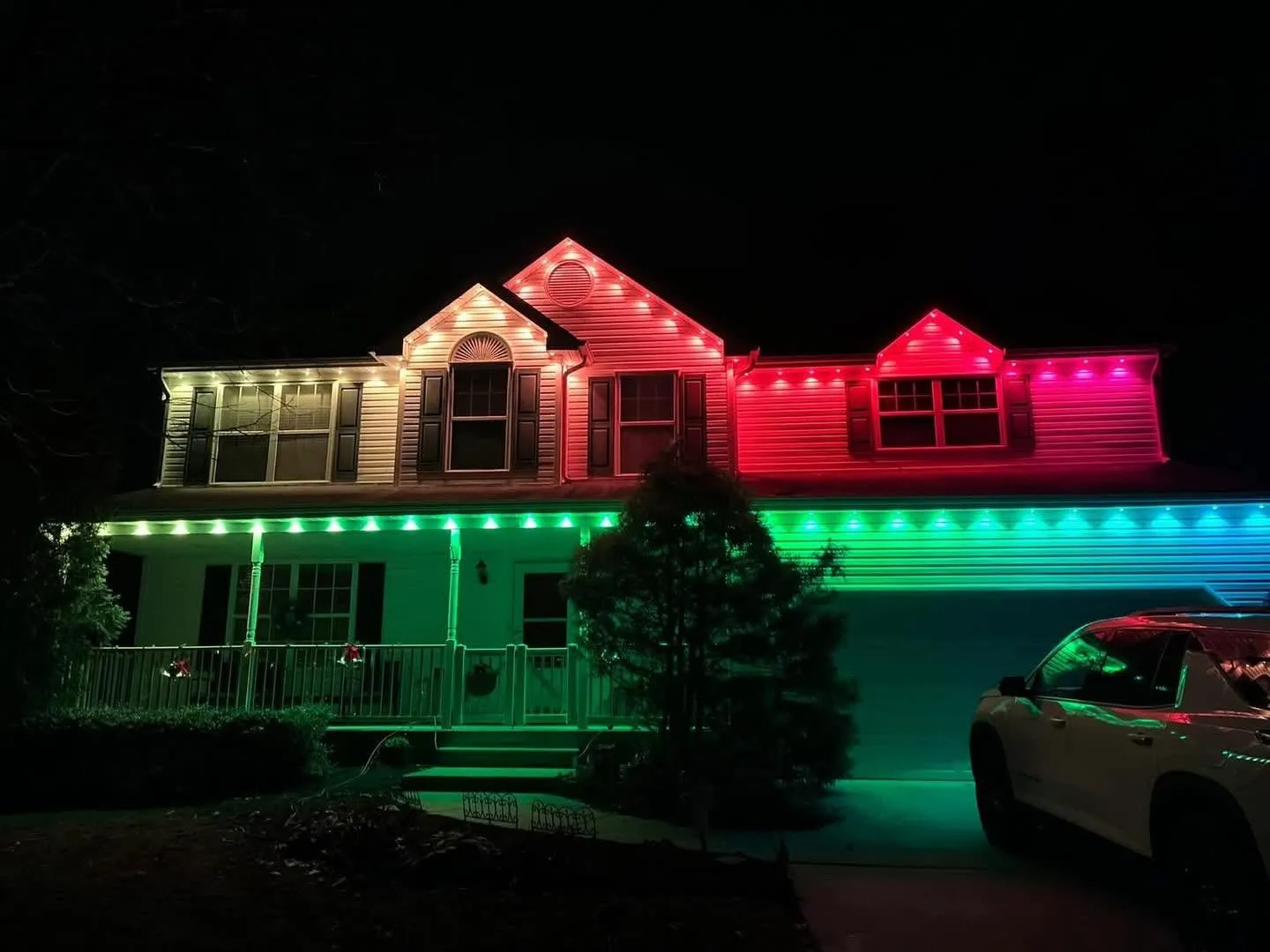 Home with white, red, and green permanent lighting sections at night