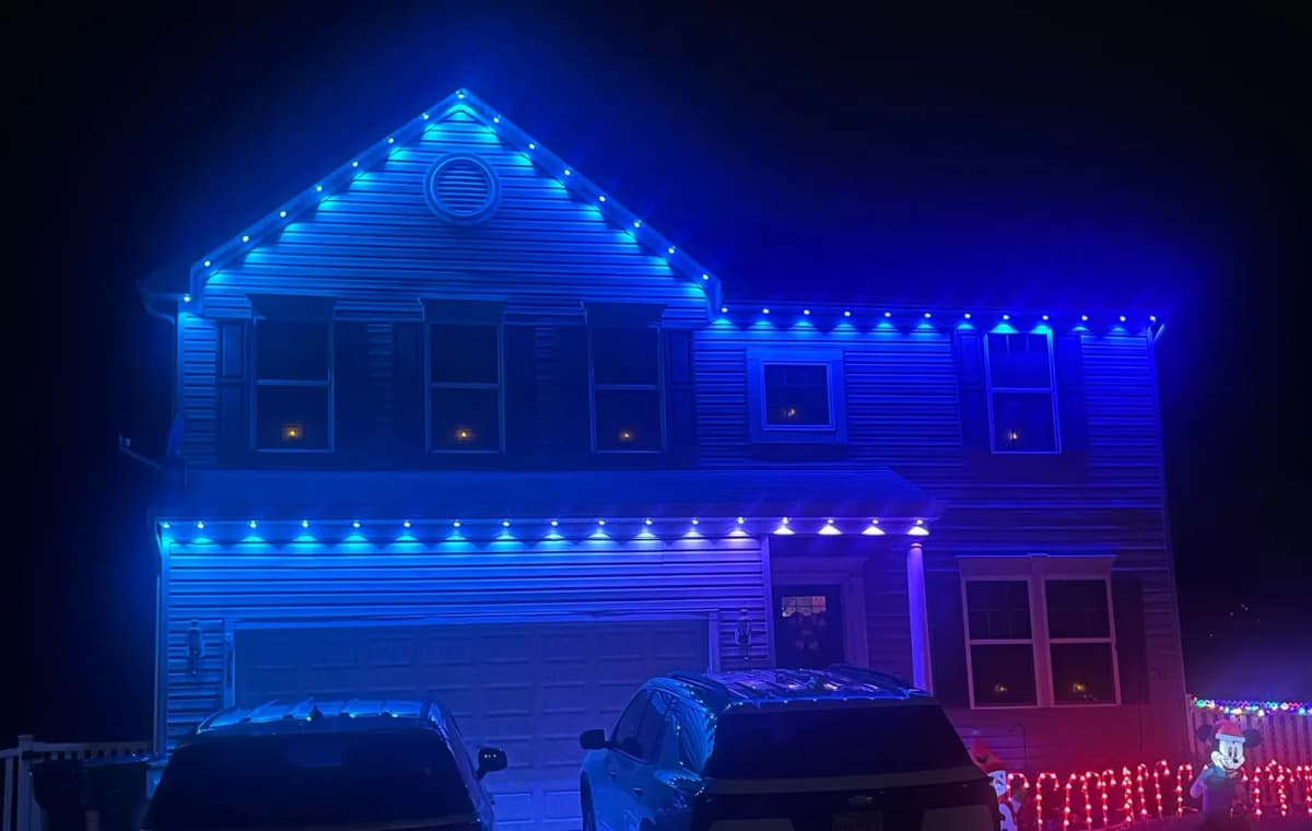 Blue Govee permanent lighting across the gables and garage line of a two-story home